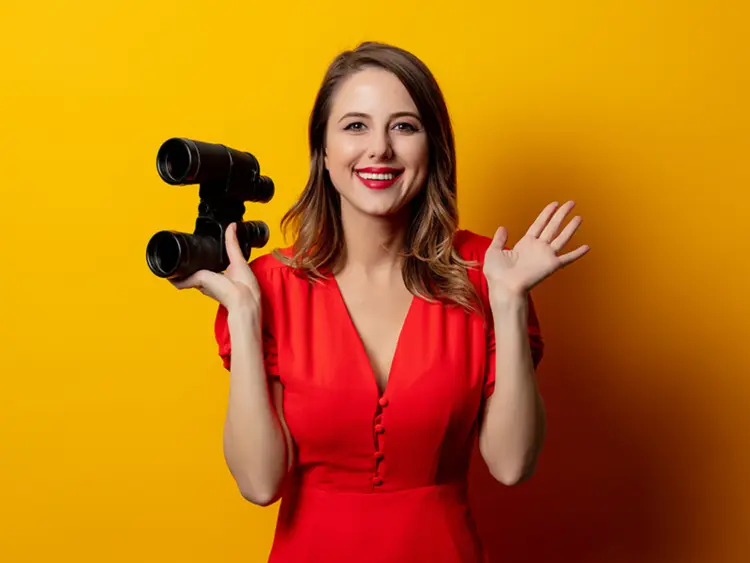 Woman in red dress holding binoculars, symbolising transparency and upfront legal details available for home buyers